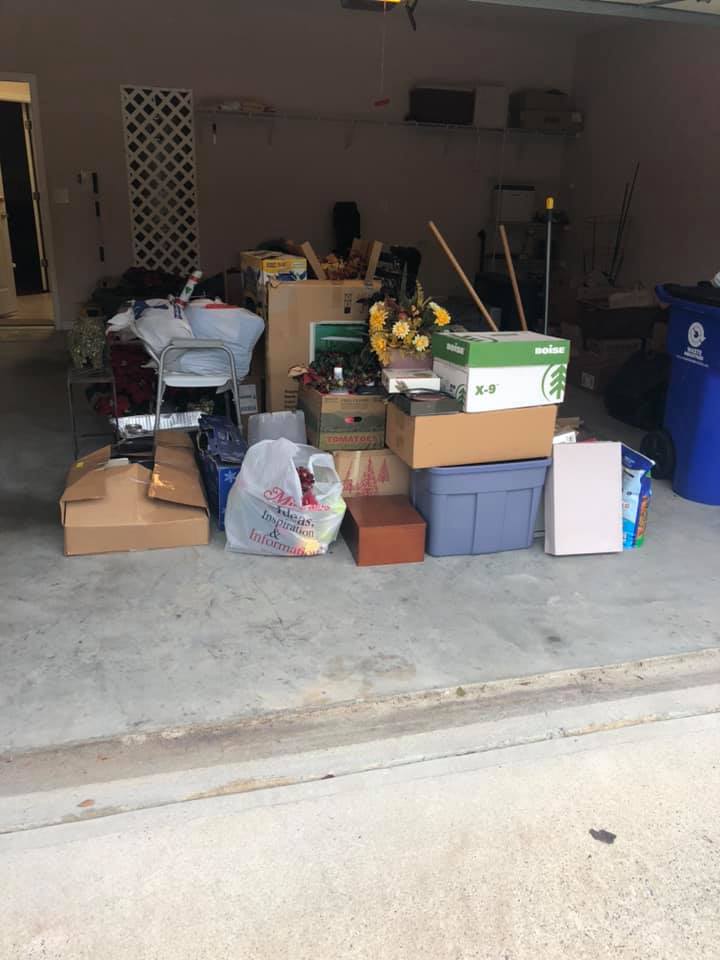 A cluttered garage filled with boxes, bags, and miscellaneous household items waiting for junk removal.