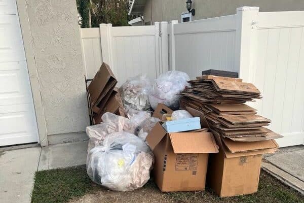 Residential junk removal service in Winter Haven, FL - pile of trash bags and flattened cardboard boxes ready for pickup.